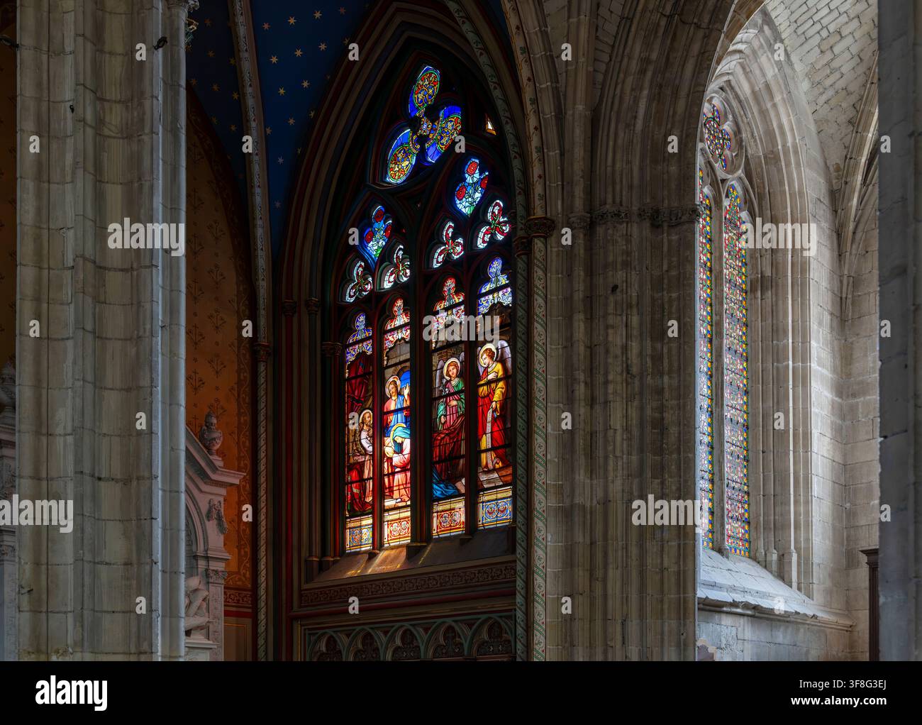 Das aufragende gotische Innere der Kathedrale von Orléans, wo Kreuzrippengewölbe, Bleiglasfenster und farbenfrohe heraldische Banner die majestätische Hauptschiffgänge säumen. Stockfoto
