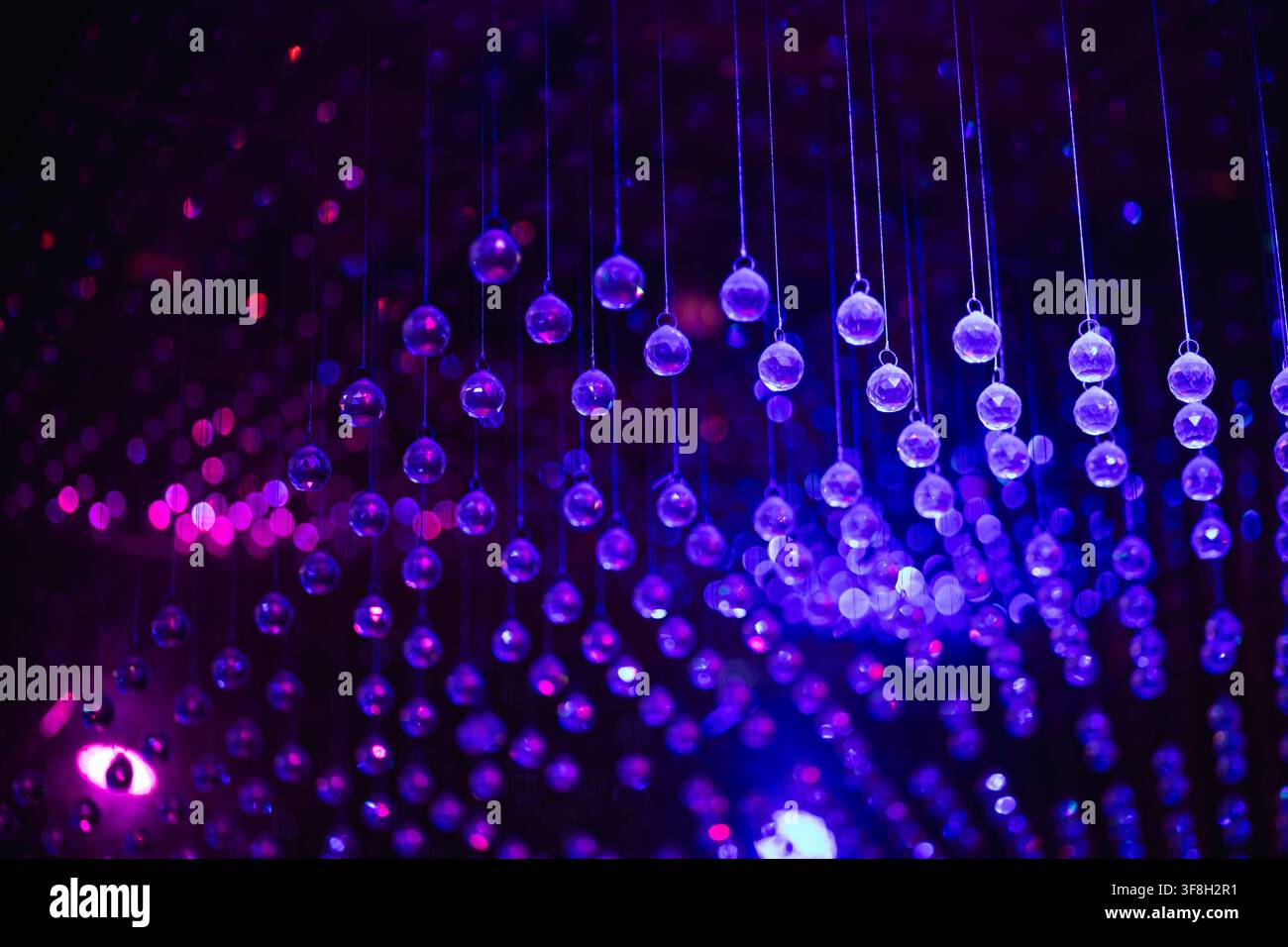 Hängende Kristallkugeln und leuchtende lila festliche Dekorationlichter Stockfoto