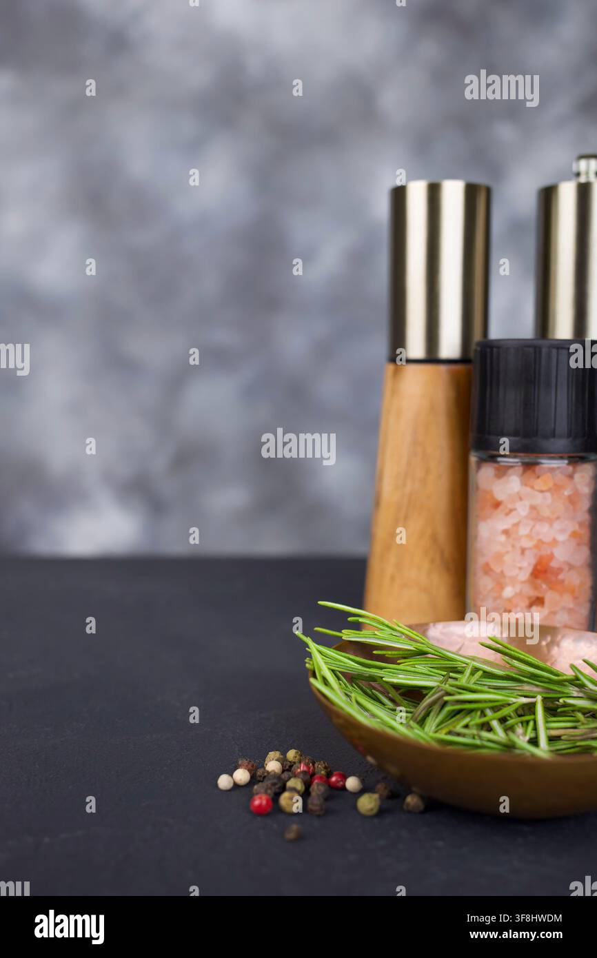 Frischer Rosmarin mit Salz- und Pfefferstreuern auf dunklem Hintergrund Stockfoto