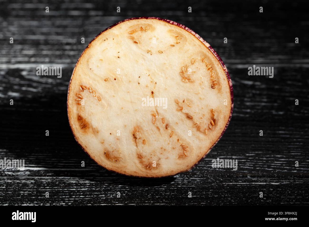 geschnittene Juwelen-Marmore-Aubergine auf schwarzem Holz-Hintergrund Stockfoto