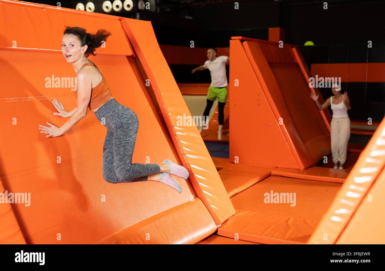 Fröhliche Frau, die auf dem Spielplatz abschüssiges Trampolin abschiebt Stockfoto