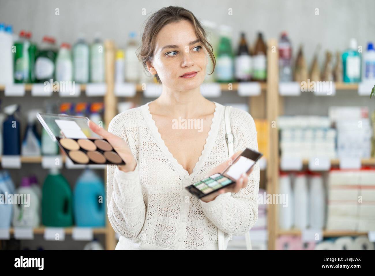 Junge Frau, die Lidschatten und Bildhauer im Laden wählt Stockfoto