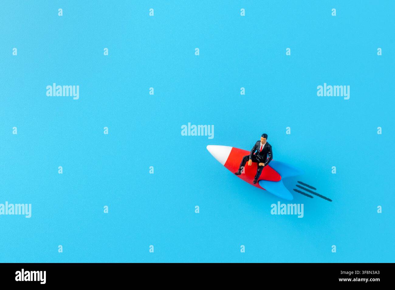 Miniatur-Geschäftsmann-Figur reitet ein Raketenschiff über einen blauen Hintergrund. Kopierraum für Text. Geschäftseröffnung, Karrieresteigerung Stockfoto