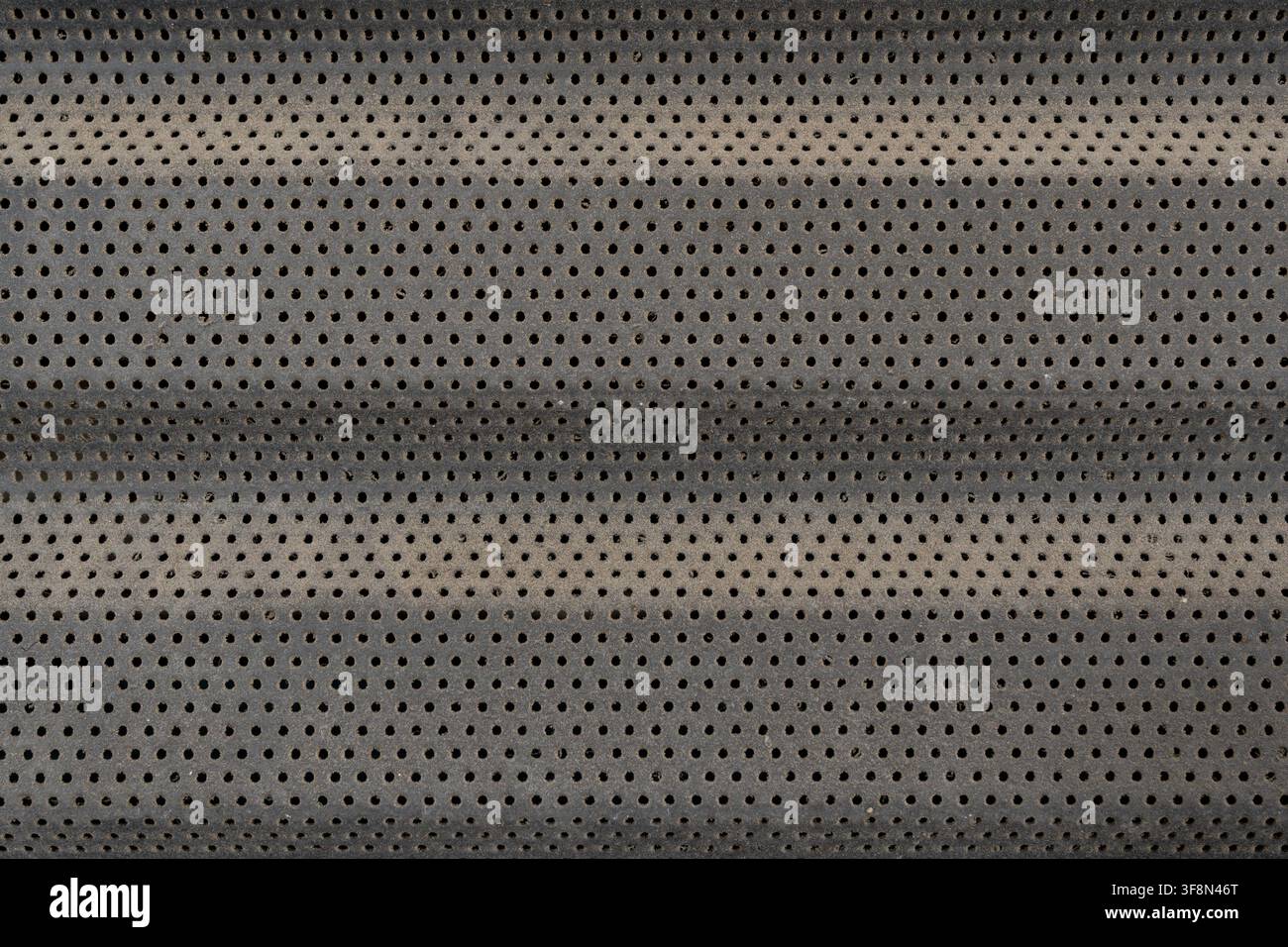 Dunkelgraue perforierte Metallplattentextur mit sich wiederholenden runden Löchern. Stockfoto