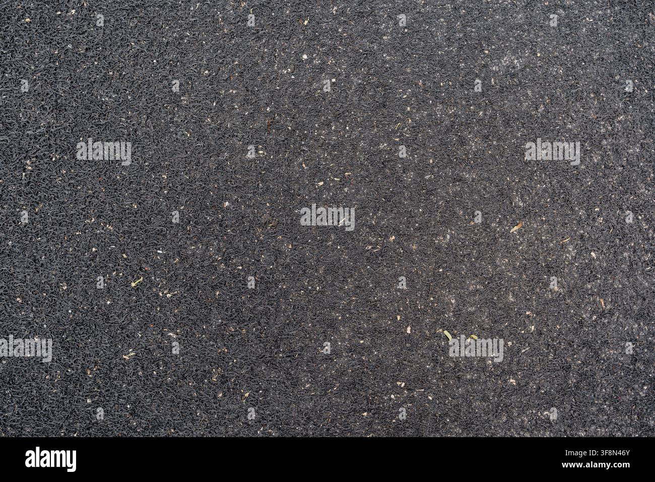 Schwarze PVC-Spiralenmatte mit verstreuter Schmutz- und Ablagerungs-Hintergrundtextur. Stockfoto