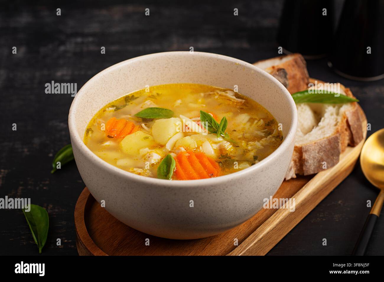 Rustikale Hühner-Orzo-Suppe in einer Schüssel auf dunklem Hintergrund Stockfoto