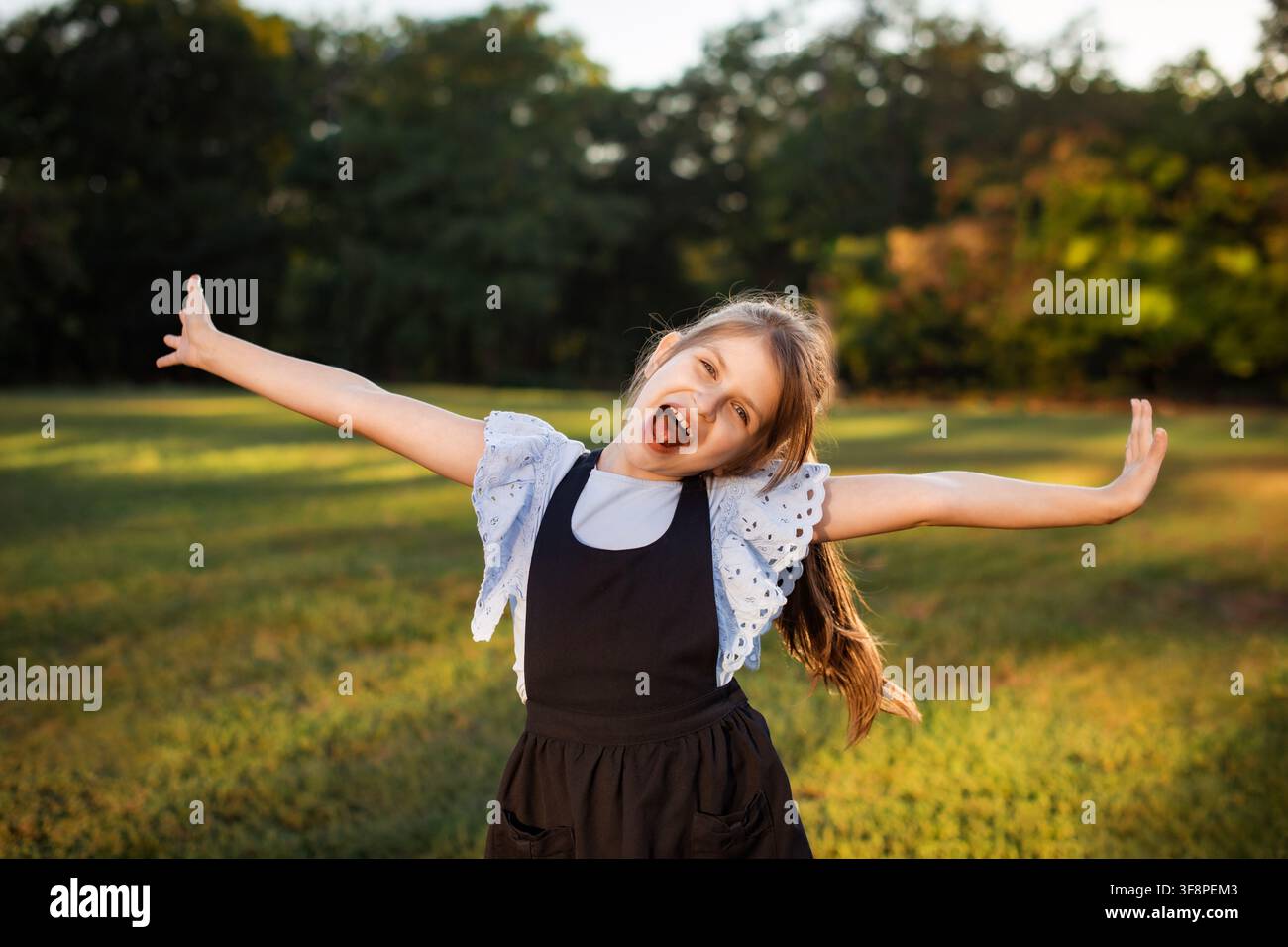 fröhliches Schulmädchen zeigt Begeisterung im Freien am ersten Schultag Stockfoto