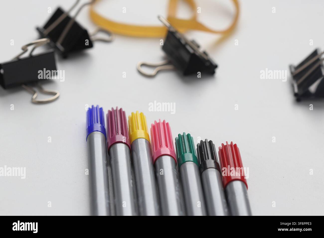 Bunte Filzstifte mit Bindeklammern und Gummiband auf weißem Hintergrund Stockfoto