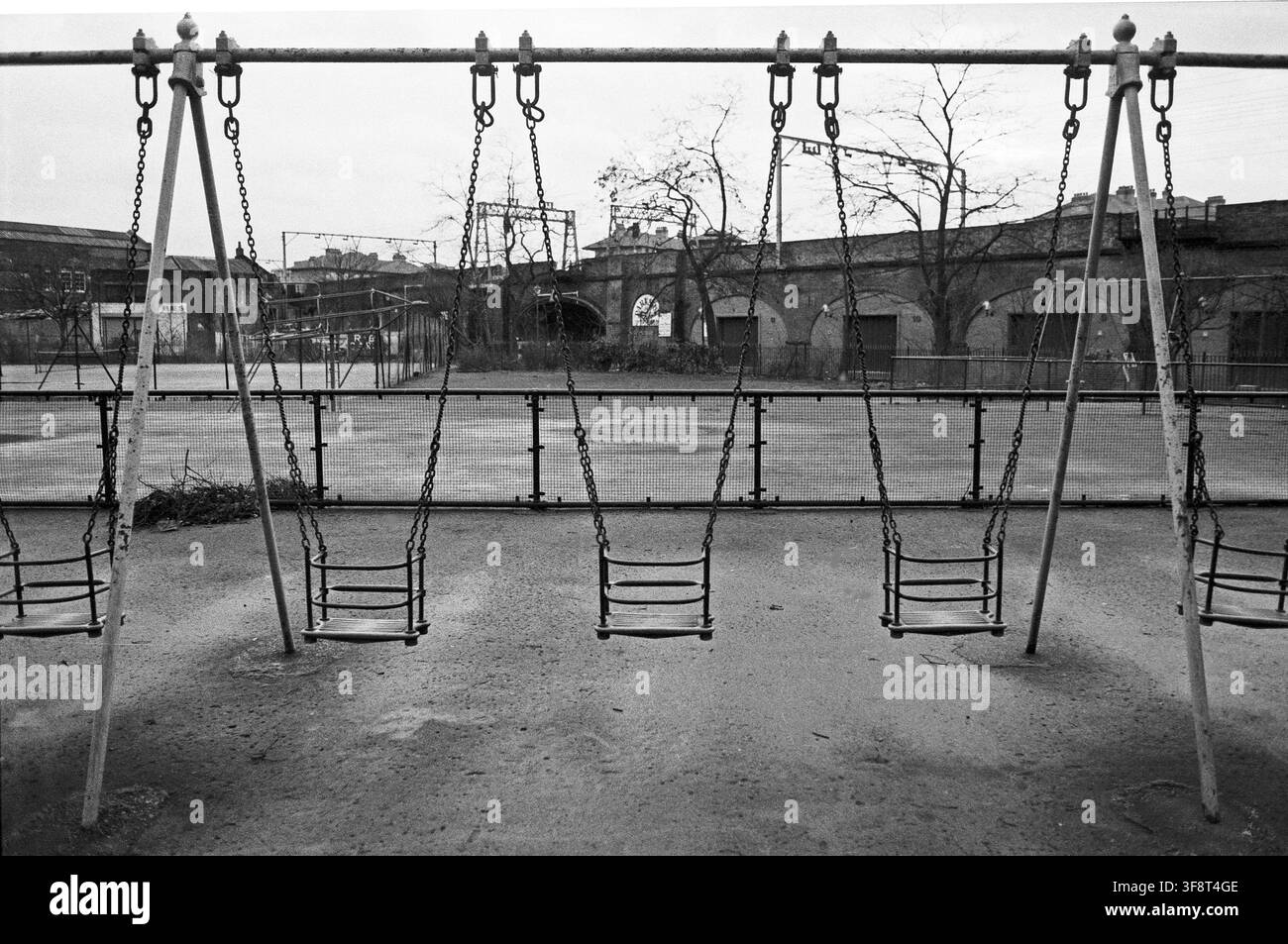 Eine Reihe leerer Kinderschaukeln in der Nähe von Bethnal Green, East London, 1990. Stockfoto