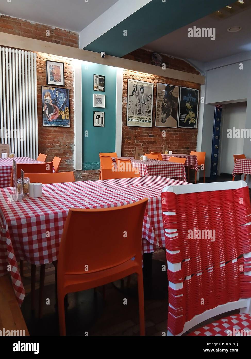 Ein leeres, gemütliches Café oder traditionelles Restaurant mit Holzstühlen und klassischen rot-weiß karierten Tischdecken. - Smartphone-aufgenommenes Stockfoto