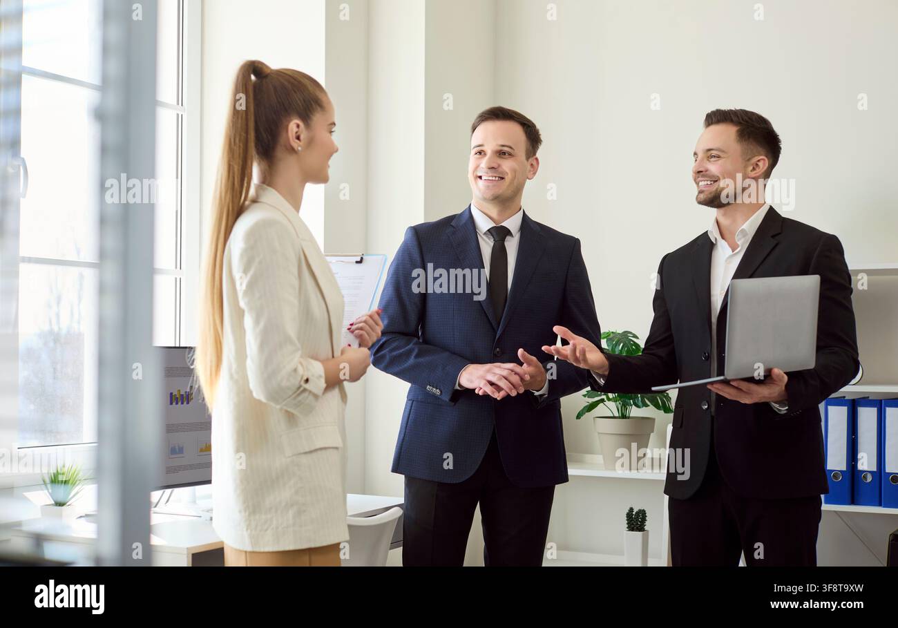 Kollegen diskutieren Strategie im modernen Büro, freundliche Begrüßung mit Laptop Stockfoto