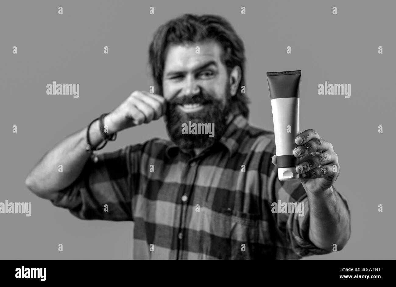 Mann hält eine Flasche Shampoo oder Duschgel. Shampoo Conditioner für Männer. Shampoo. Attraktiver Mann trägt Cremelotion auf. Schwarz und Weiß Stockfoto