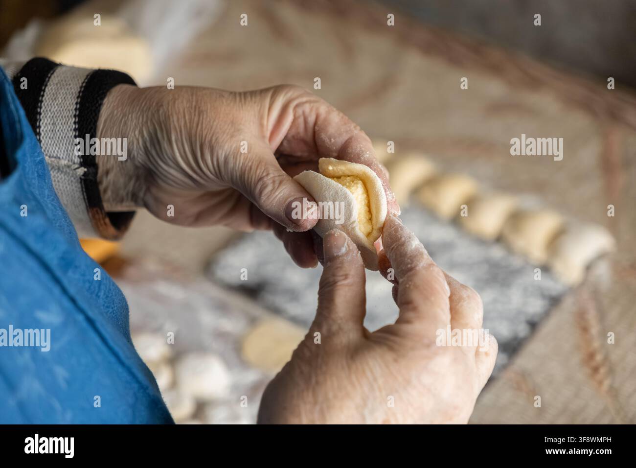 Ein älteres Paar Hände versiegelt geschickt Teig um eine herzhafte Füllung, um einen Knödel zu formen, und betont rustikale Kochtraditionen, handwerkliches Erbe Stockfoto
