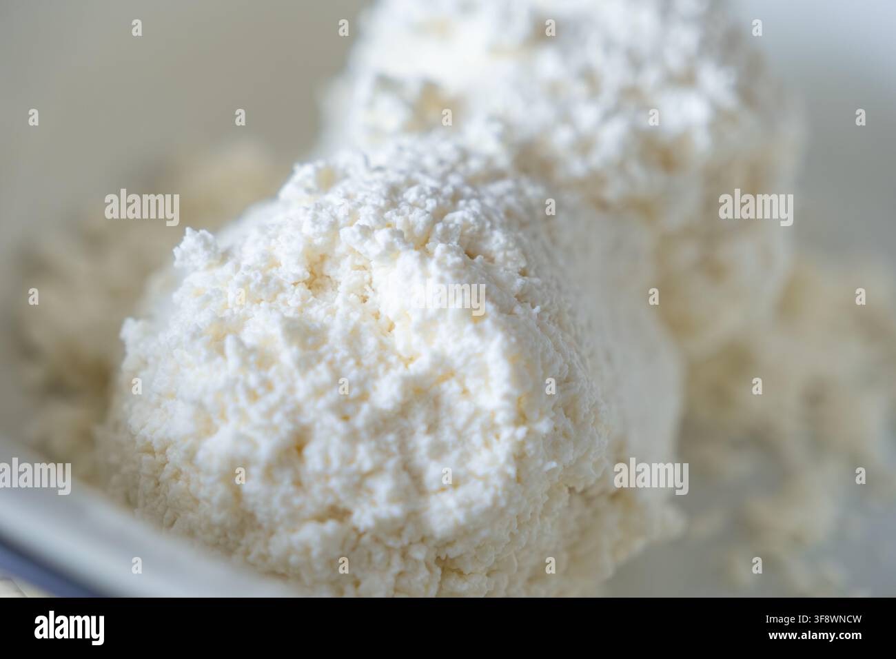 Weiche Hüttenkäse-Klumpen in einer Nahaufnahme zeigen die bröcklige Oberfläche eines beliebten Milchprodukts, das als vielseitiger Bestandteil dient Stockfoto