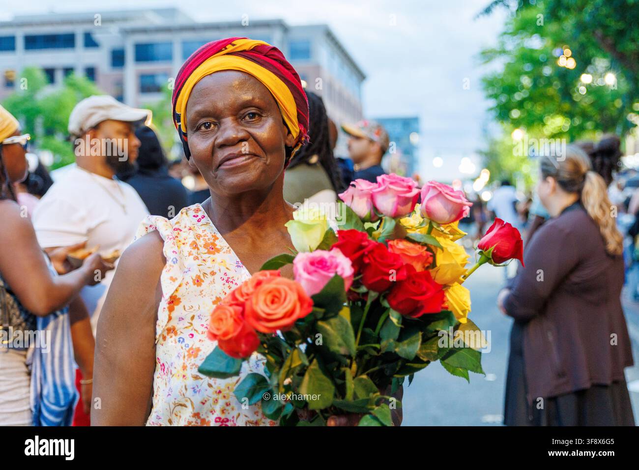 Eine Straßenhändlerin hält einen Blumenstrauß, den sie während Veranstaltungen in Syracuse, NY, verkauft. Stockfoto