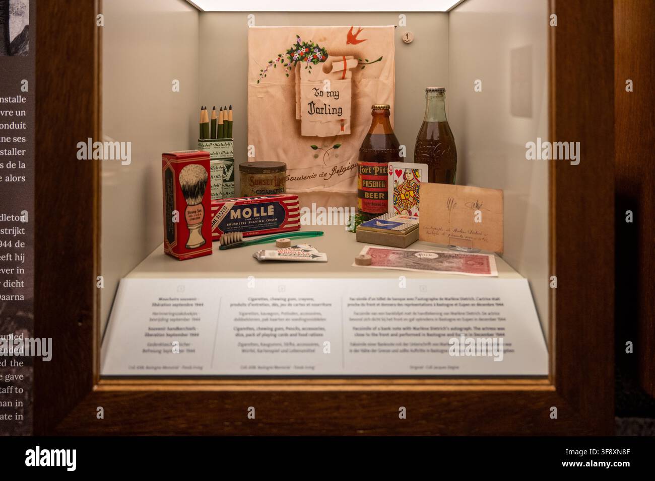Bastone, Belgien – 21. Jul 25: Vitrine mit Kriegssouvenirs, Schreibwaren, Bierflaschen, Karten und persönlichen Gegenständen in den Bastogne War Rooms in Belgien Stockfoto