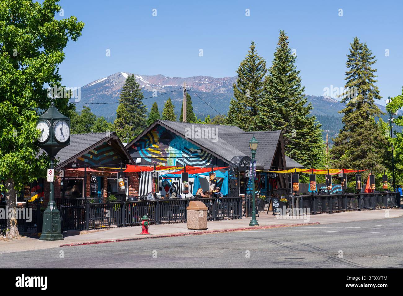 Gäste, die auf der farbenfrohen Außenterrasse des Drizzle-Burgerrestaurants unter einem klaren blauen Himmel in der Innenstadt von Mount Shasta, Kalifornien, speisen Stockfoto