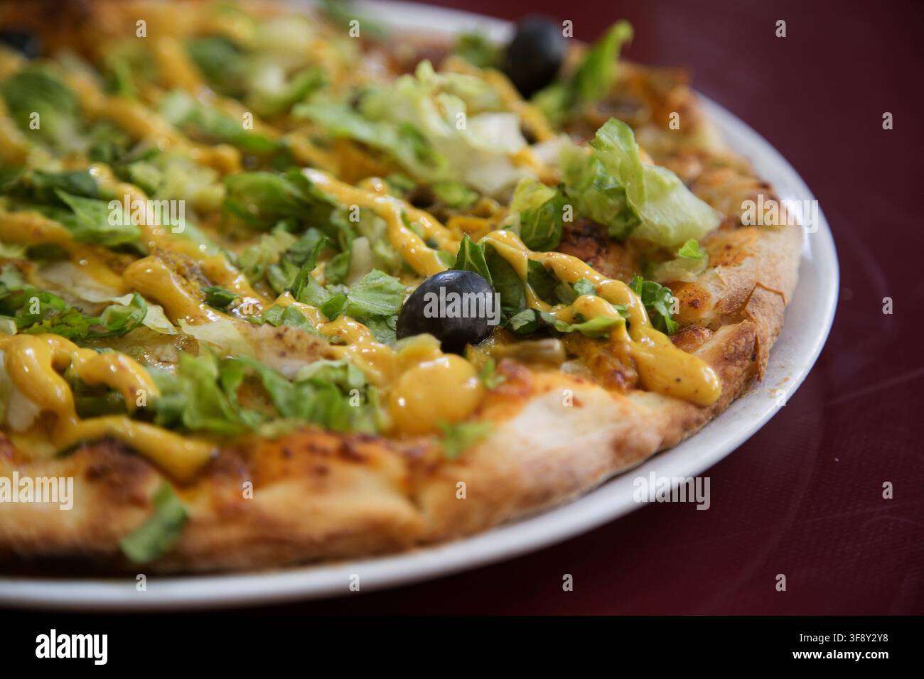Pizza im indischen Stil mit Huhn und Currysauce und Salatblättern Stockfoto