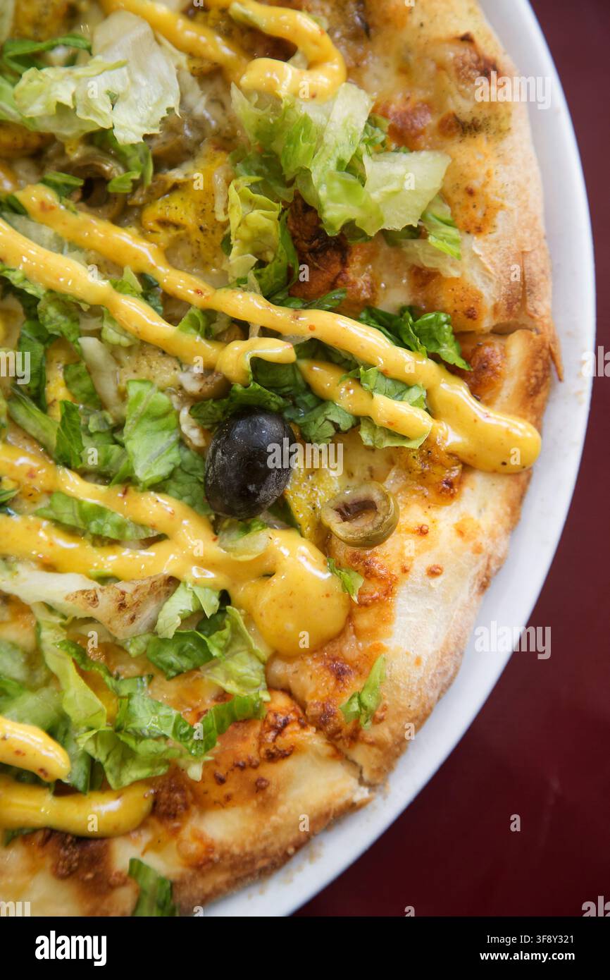 Pizza im indischen Stil mit Huhn und Currysauce und Salatblättern Stockfoto