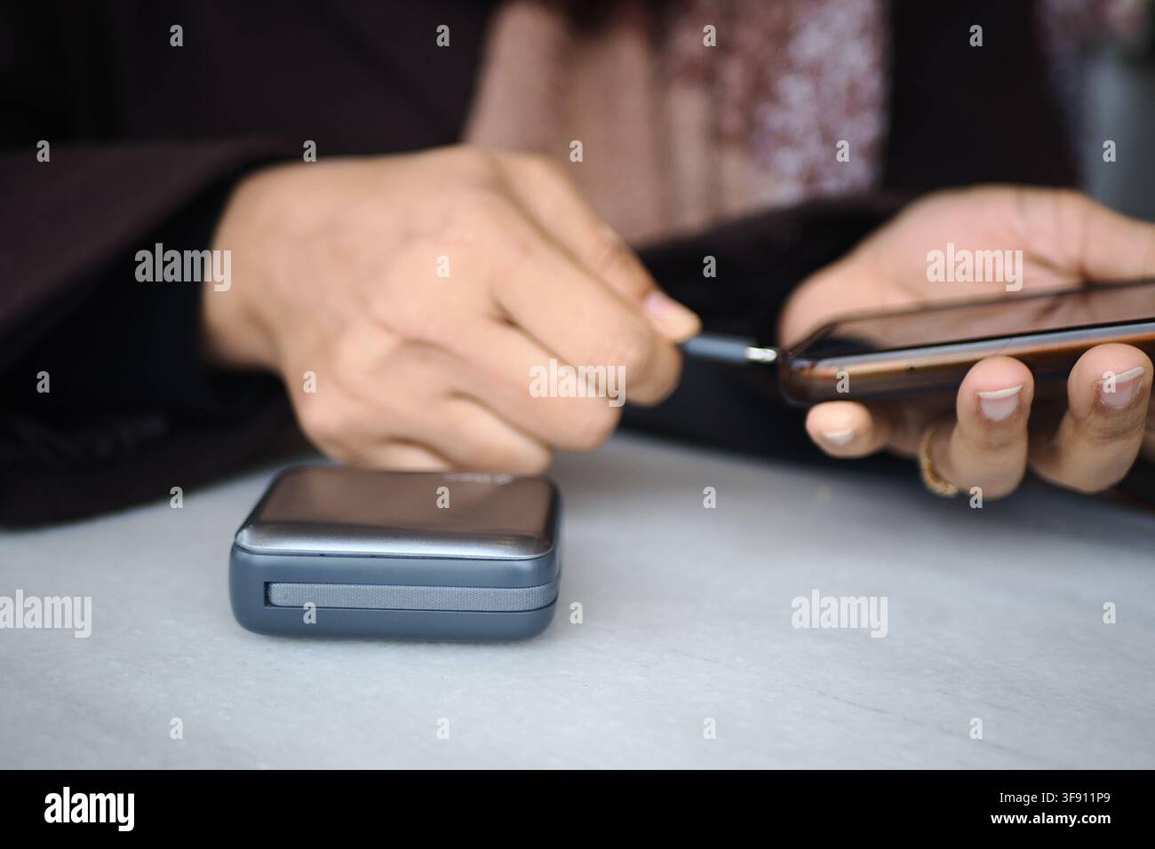 eine junge Frau lädt ein Smartphone mit einer Powderbank auf. Stockfoto