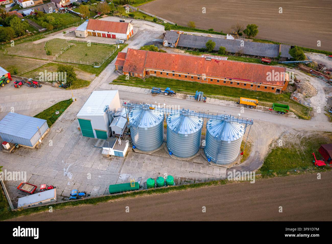 Luftaufnahme von Getreidesilos und landwirtschaftlichen Gebäuden in einer ländlichen Farmumgebung mit Traktoren und Feldern in Chvalkovice, Region Hradec Kralove, Tschechien. Stockfoto