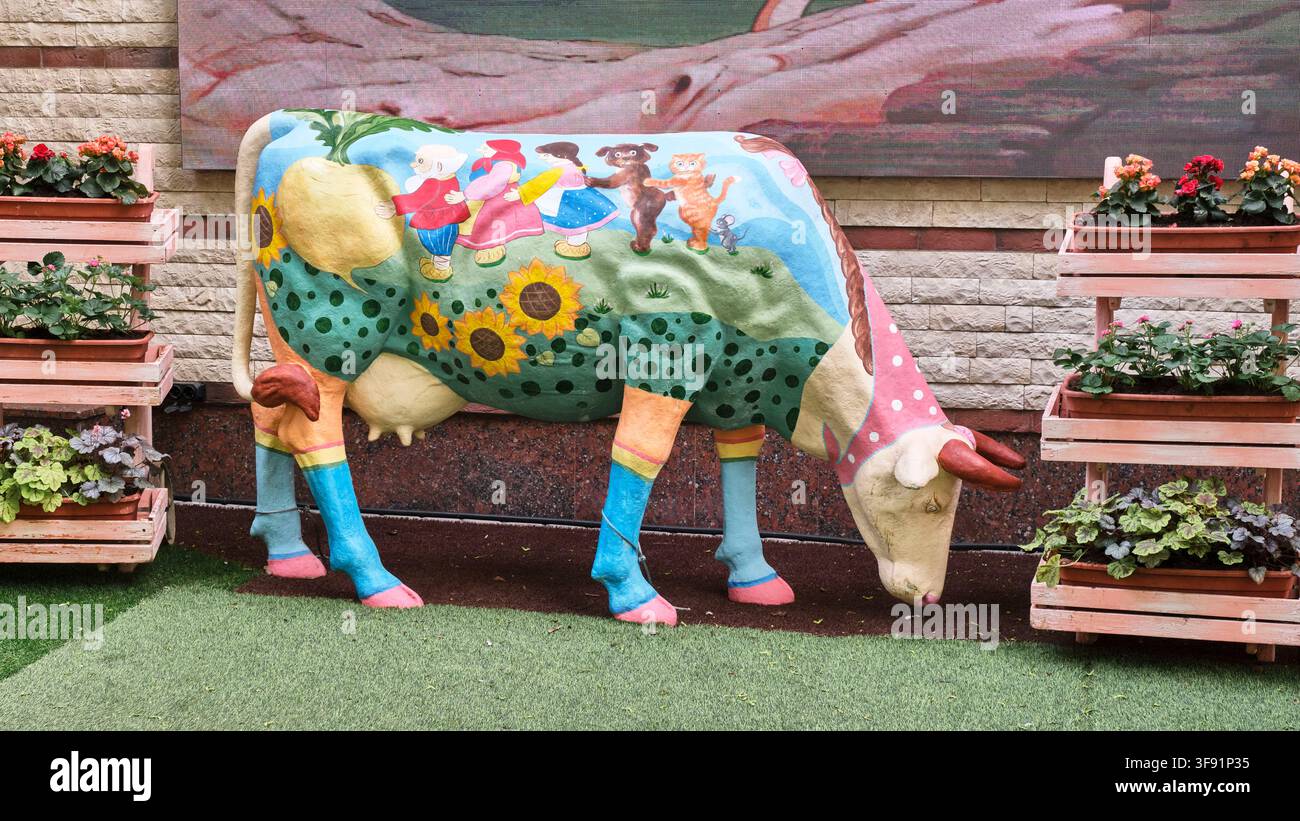 Gemalte Kuhskulptur mit Märchenillustration im Stadtpark Stockfoto
