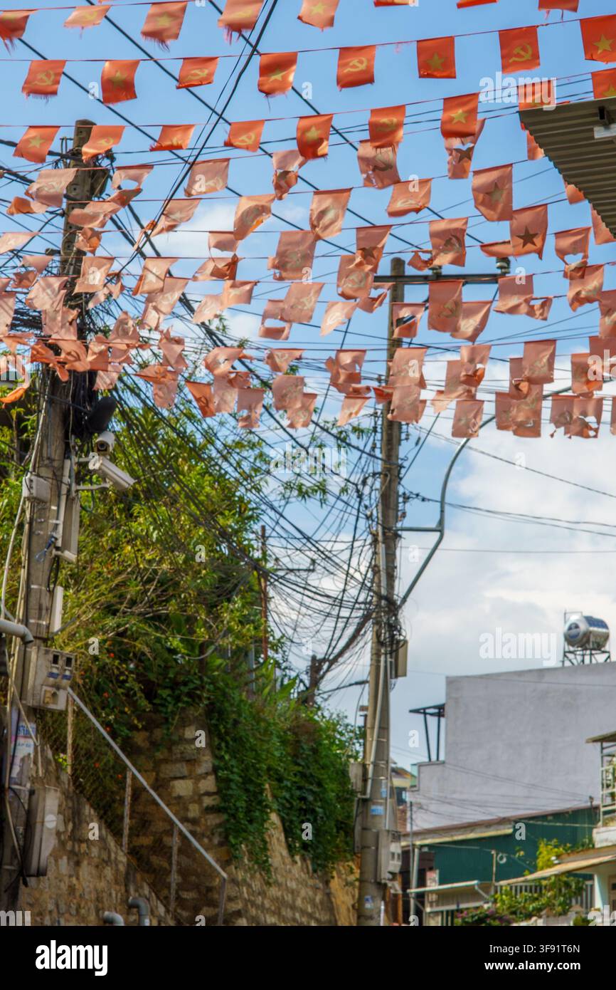 Rote Fahnen, die am helllichten Tag über einer städtischen Straße hängen. Stockfoto