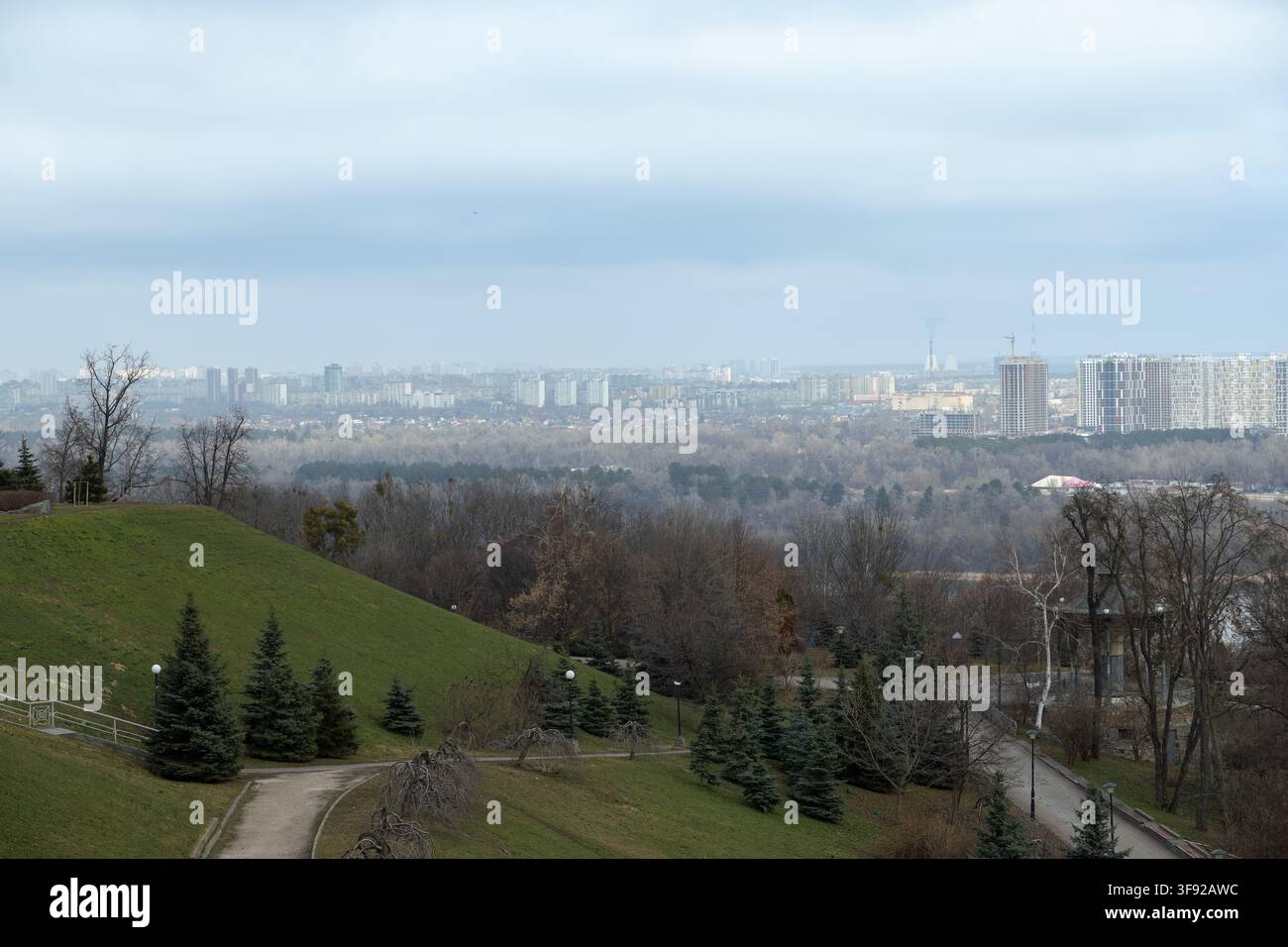 Stadt-Skyline erhebt sich über einen üppigen grünen Park mit sanften Hügeln und Nadelwald in einer städtischen Umgebung, der eine ausgewogene Mischung aus Archi widerspiegelt Stockfoto