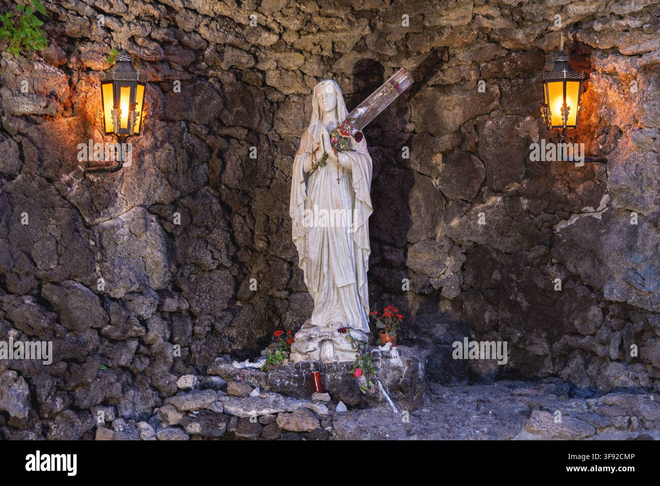 Statue der Jungfrau Maria in einer beleuchteten Steingrotte Stockfoto