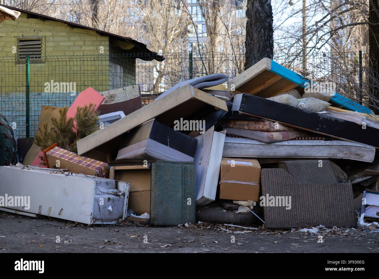 Massive Sammlung von zerbrochenen Möbeln, abgenutzten Matratzen und Schrottmaterial, das in einem Wohnhof entsorgt wurde, symbolisiert Verfall, Probleme des Abfallmanagements Stockfoto
