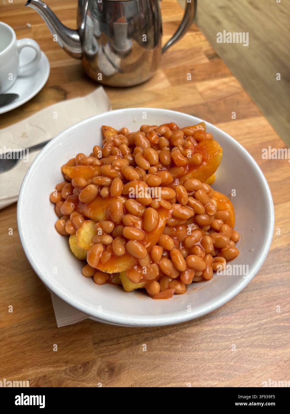 Eine große Schüssel mit Chips und gebackenen Bohnen, eine Lieblingsmahlzeit vieler.. Stockfoto