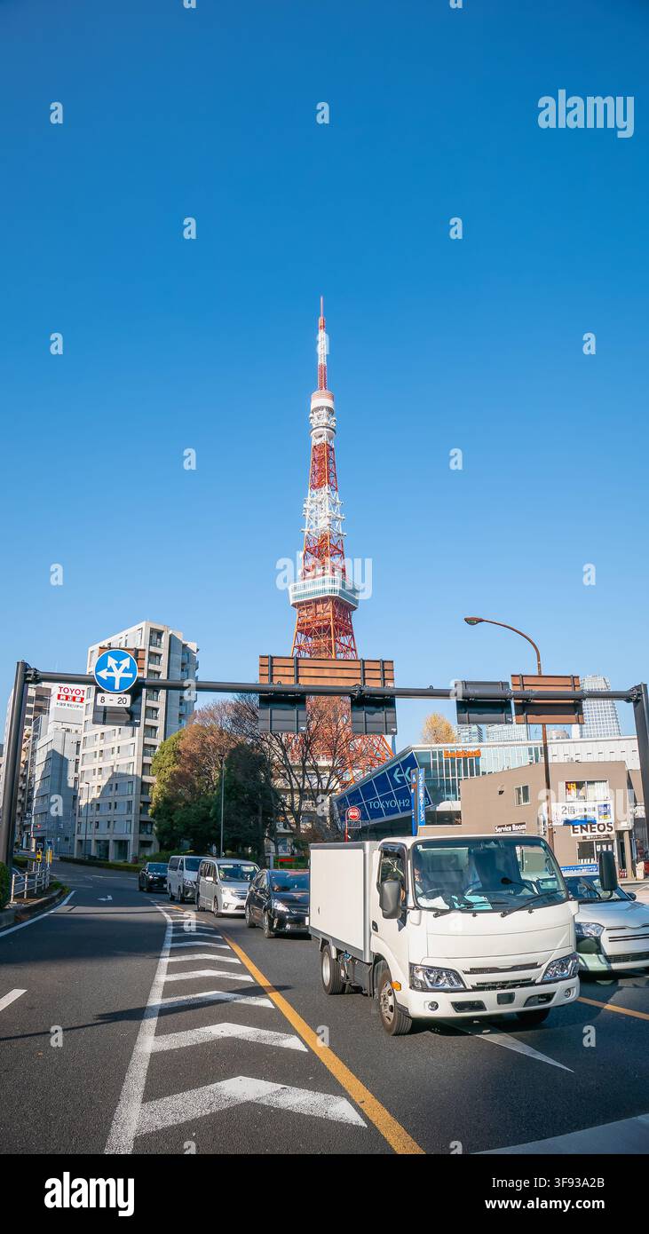 Tokio, Japan – 30. Dezember 2025: Der Verkehr fließt nahe der Akabanebashi-Kreuzung, während sich der ikonische Tokyo Tower in einen klaren blauen Himmel erhebt. Stockfoto