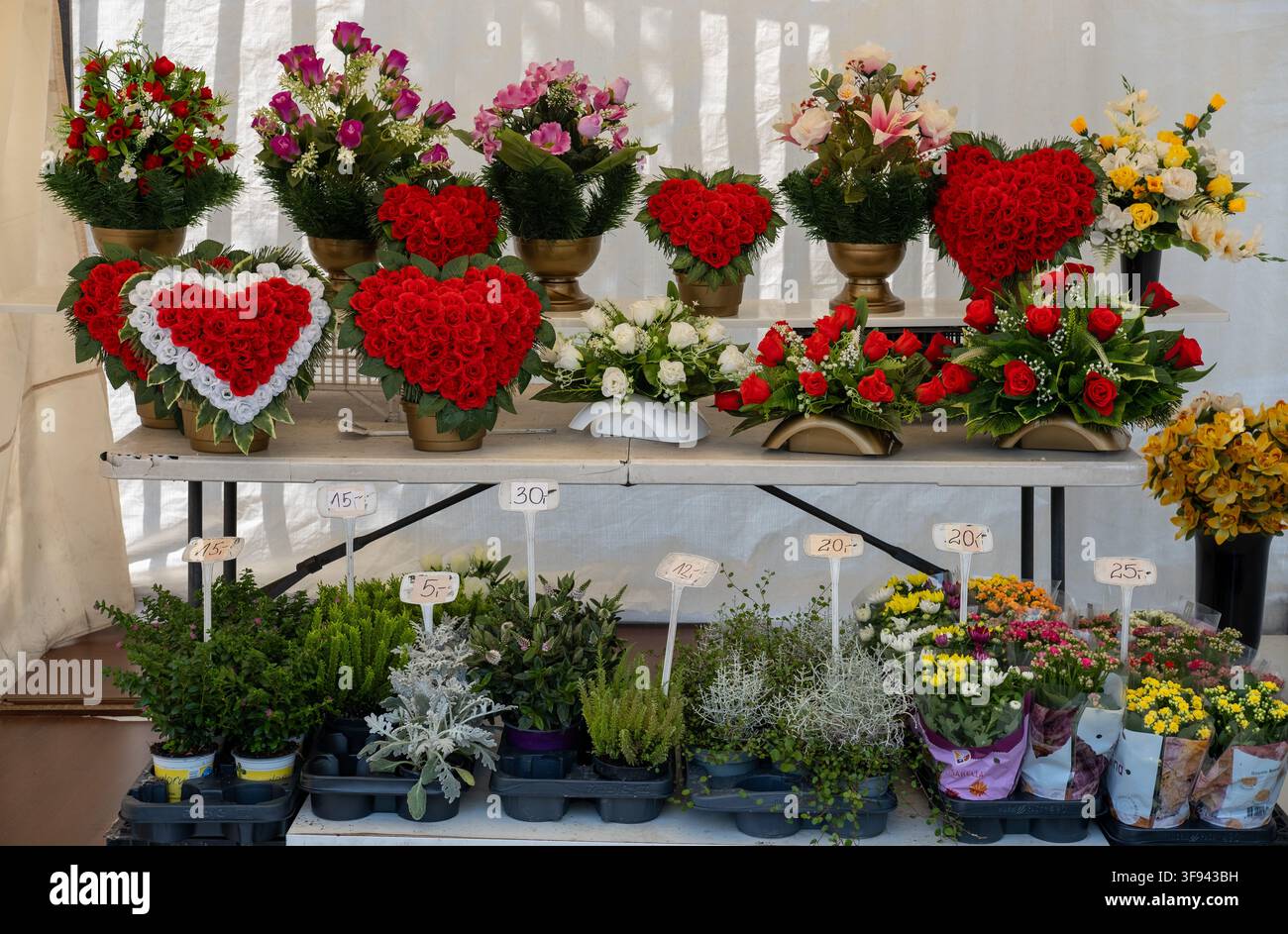 Blumenarrangements, Kränze und Topfpflanzen werden an einem Marktstand im Freien zum Verkauf angeboten. Stockfoto