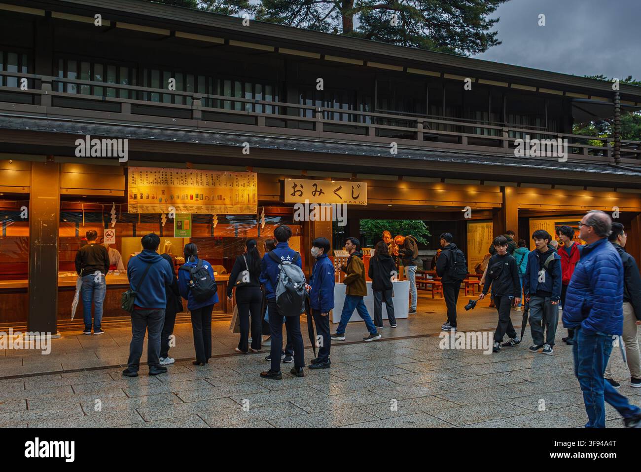 Touristen kaufen traditionelle Omikuji-Glückspapiere an der Holztheke im Meiji-Schrein in Tokio, Japan. Stockfoto