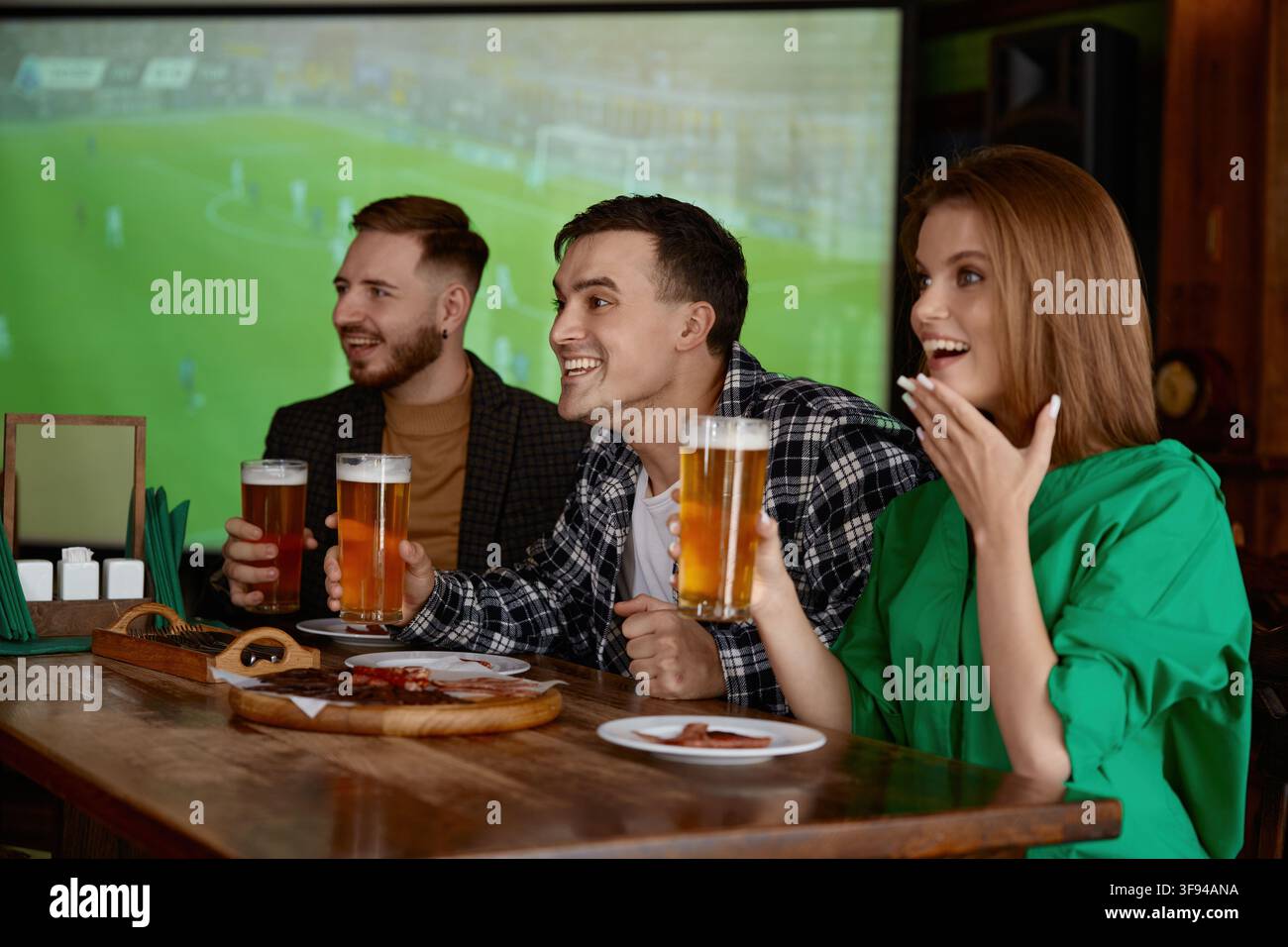 Gruppe von Freunden, die in einer Kneipe begeistert ihre Biergläser anstoßen Stockfoto