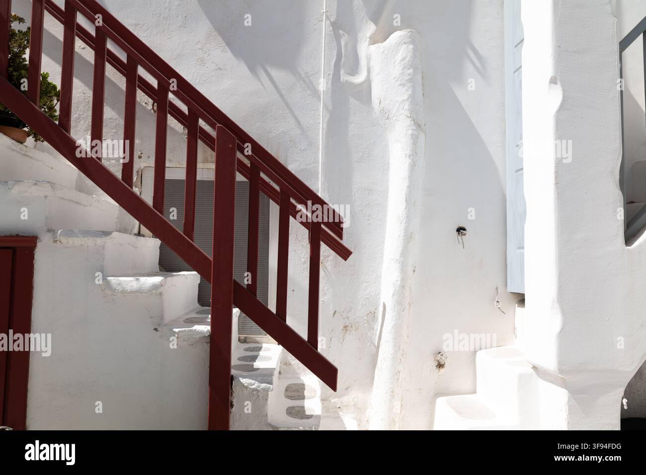 Tiefrot gestreifte Treppe vor einer weißen Wand, Mykonos, Griechenland. Stockfoto