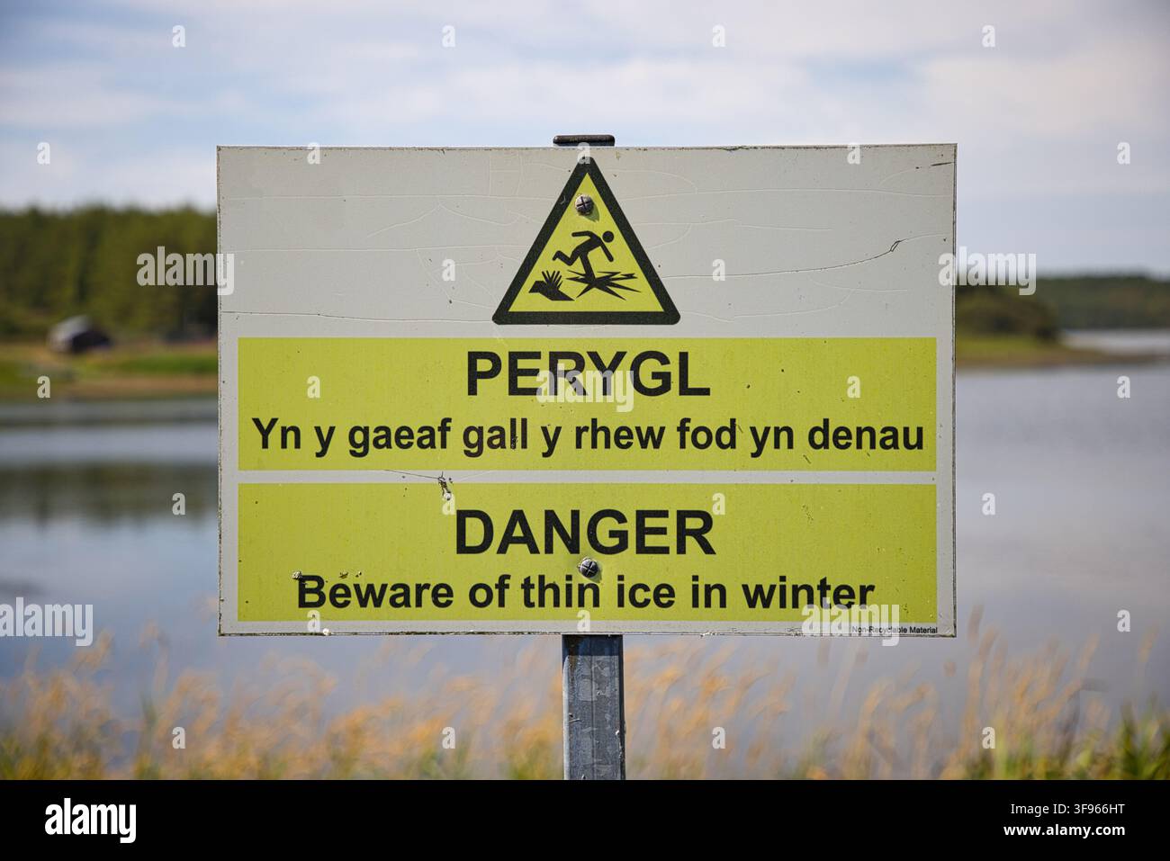 Bilinguales walisisch-englisches Warnschild bezüglich dünner Eisdecke während des Winters am Llyn Cefni-Reservoir, Nordwales, Anglesey. Stockfoto