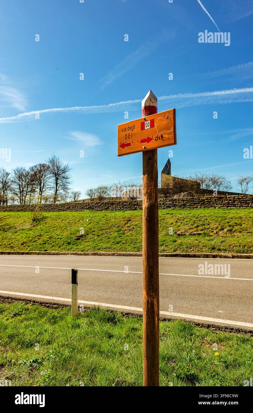 Schild für den „Weg der Götter“ nahe dem Futa-Pass. Im Hintergrund der Friedhof Germani mit seinem unverwechselbaren Gipfeldenkmal. Stockfoto