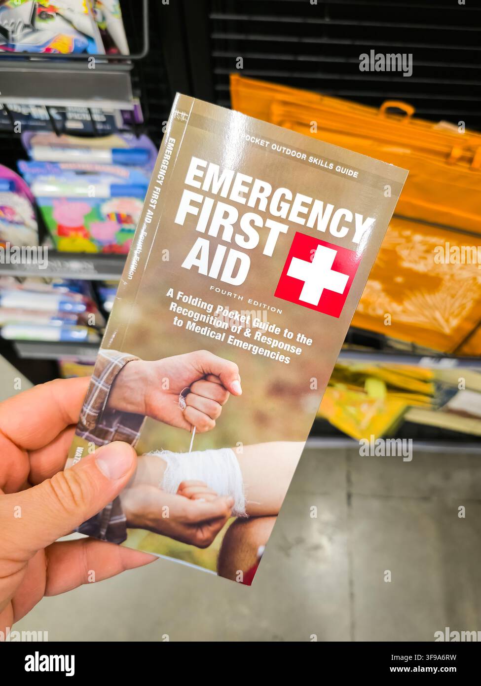 PLANO, TX, USA - 29. JULI 2026: Eine Person hält den 'Notfall-Erste-Hilfe'-Taschenführer in einem Geschäft. Das Heft bietet wesentliche Anweisungen für die Reaktionsmaßnahmen Stockfoto