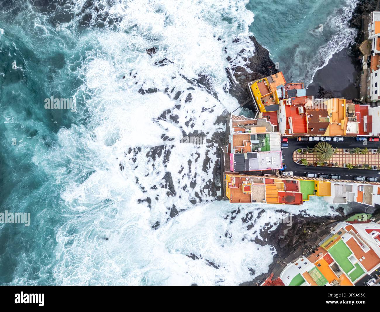Luftbild von oben über wilde Wellen im Atlantischen Ozean mit farbenfrohen Häusern auf der Insel Teneriffa in Puerto de la Cruz, Spanien Stockfoto