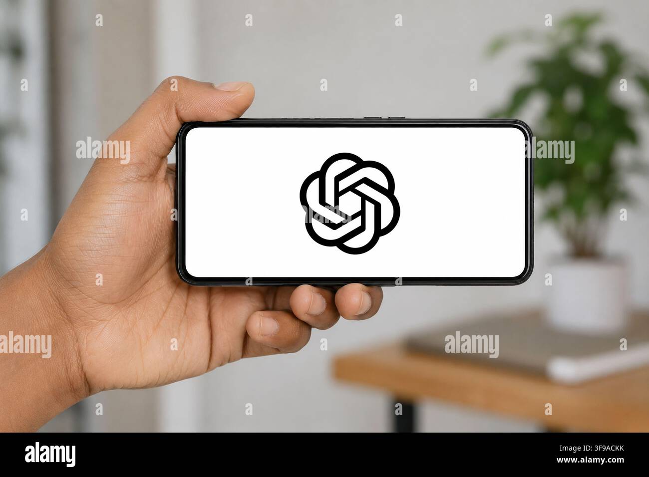 15. August 2026: In dieser Fotoillustration hält eine Hand ein Smartphone horizontal, das das ChatGPT-KI-Logo anzeigt, vor einem sanft verschwommenen Innenhintergrund, in Indien am 15. August 2026. (Bildnachweis: © David Talukdar/ZUMA Press Wire) NUR FÜR REDAKTIONELLEN GEBRAUCH! Nicht für kommerzielle VERWENDUNG! Stockfoto