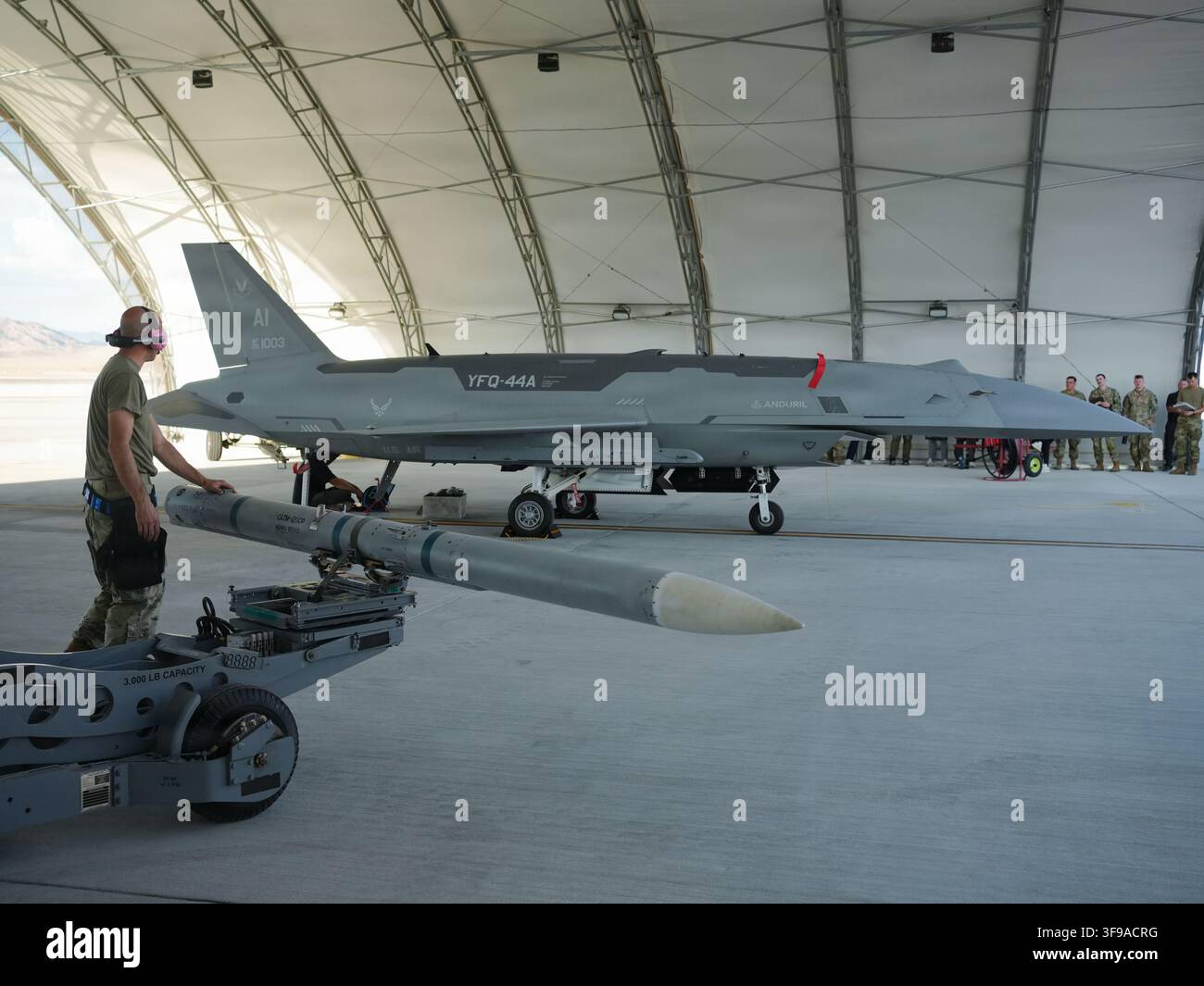 Ein U.S. Airman, der der Collaborative Combat Aircraft Experimental Operations Unit zugeteilt ist, bereitet das Laden einer inerten Rakete auf ein YFQ-44A Fury Flugzeug vor Stockfoto