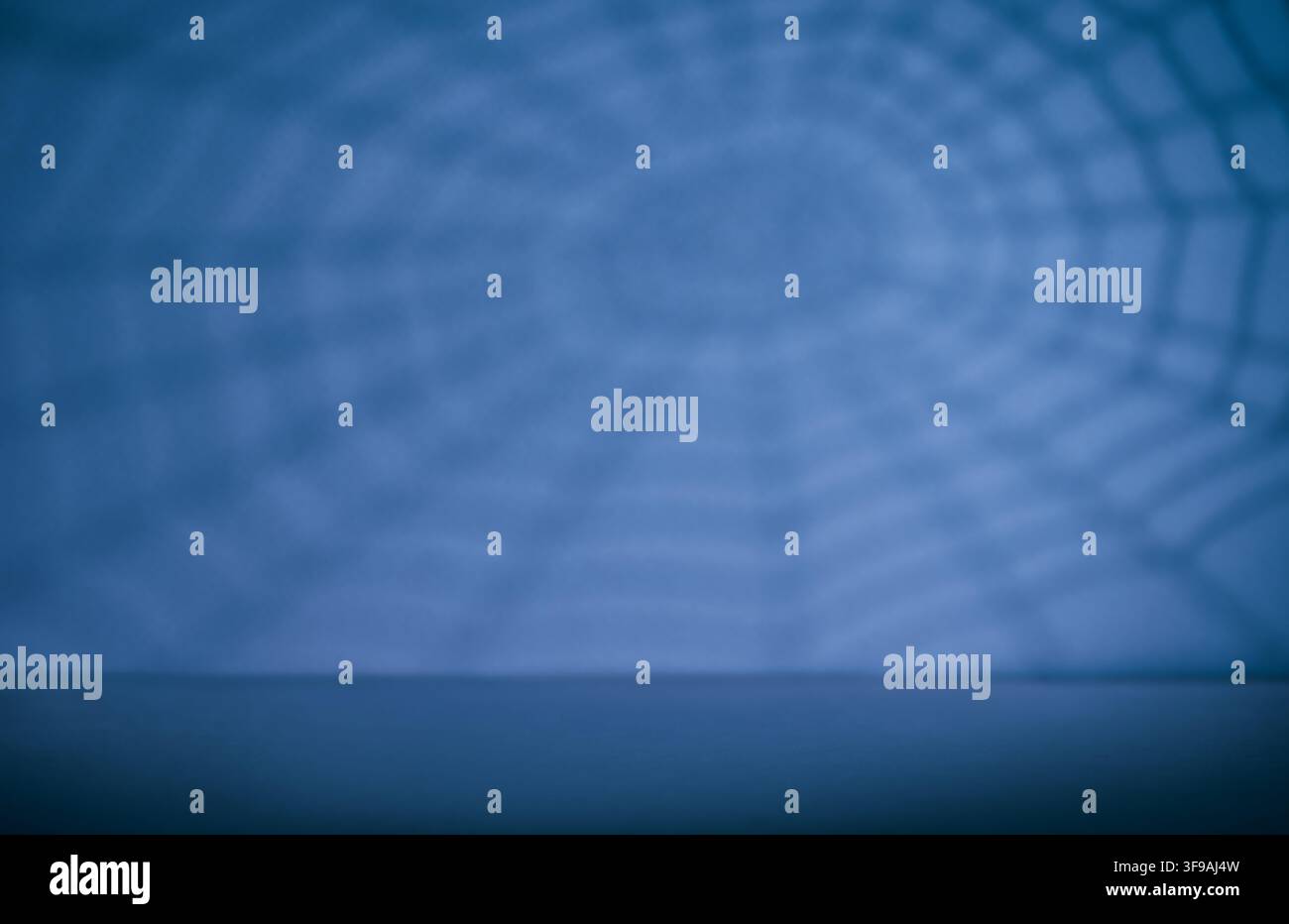 Blauer Hintergrund mit Spinnennetz-Schatten und leerer Tischplatte für Halloween-Produkt-Mockup-Party-Banner oder saisonale Ausstellung Stockfoto