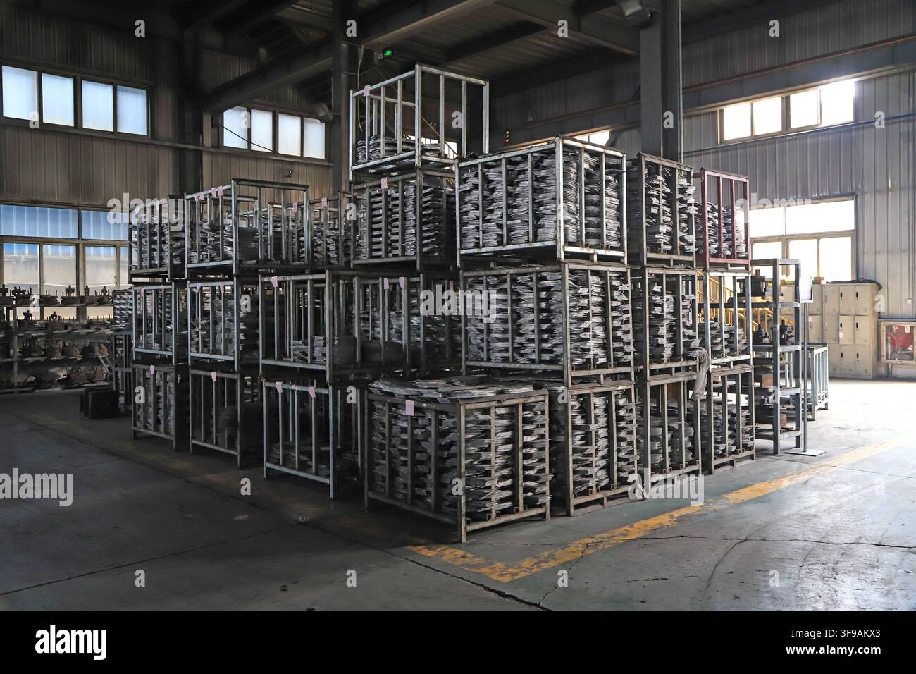 Das Bild zeigt das Innere eines industriellen Fabriklagers, in dem Rohmaterialien für die Schaufelproduktion ordentlich in mehrschichtigen Metallregalen gestapelt sind Stockfoto