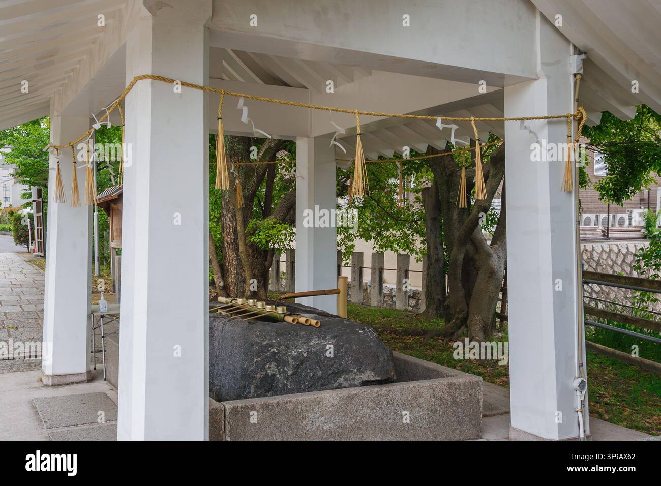 Außenansicht eines historischen japanischen Schrein-Wasserbassins mit Bambuslöffeln für die rituelle Reinigung in Osaka, Japan. Stockfoto