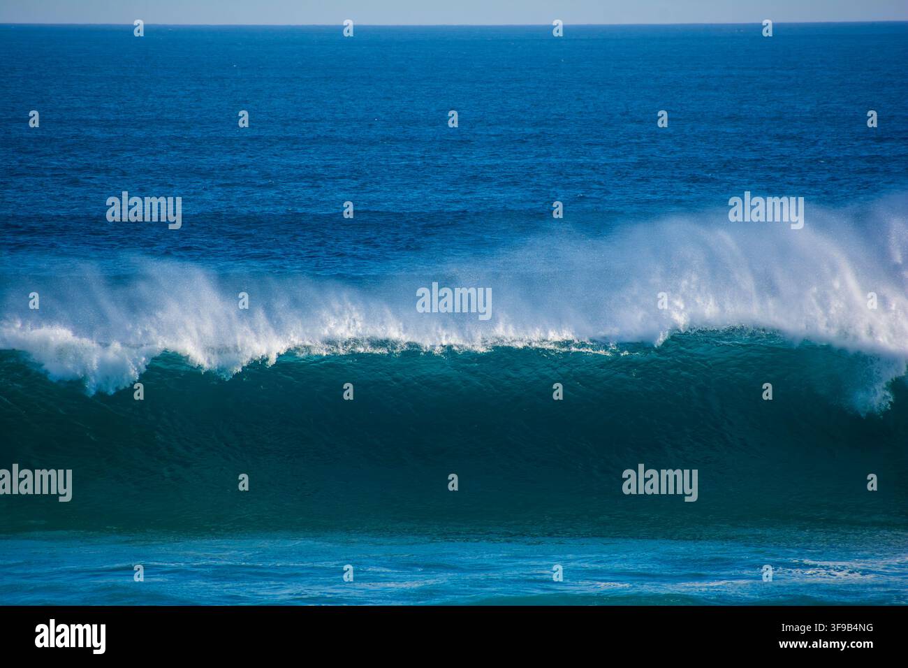 Eine brechende Welle wirft eine Fontäne aus Meeresspritzwasser an der ANZACs Beach, Phillip Island, Victoria, Australien auf. Stockfoto