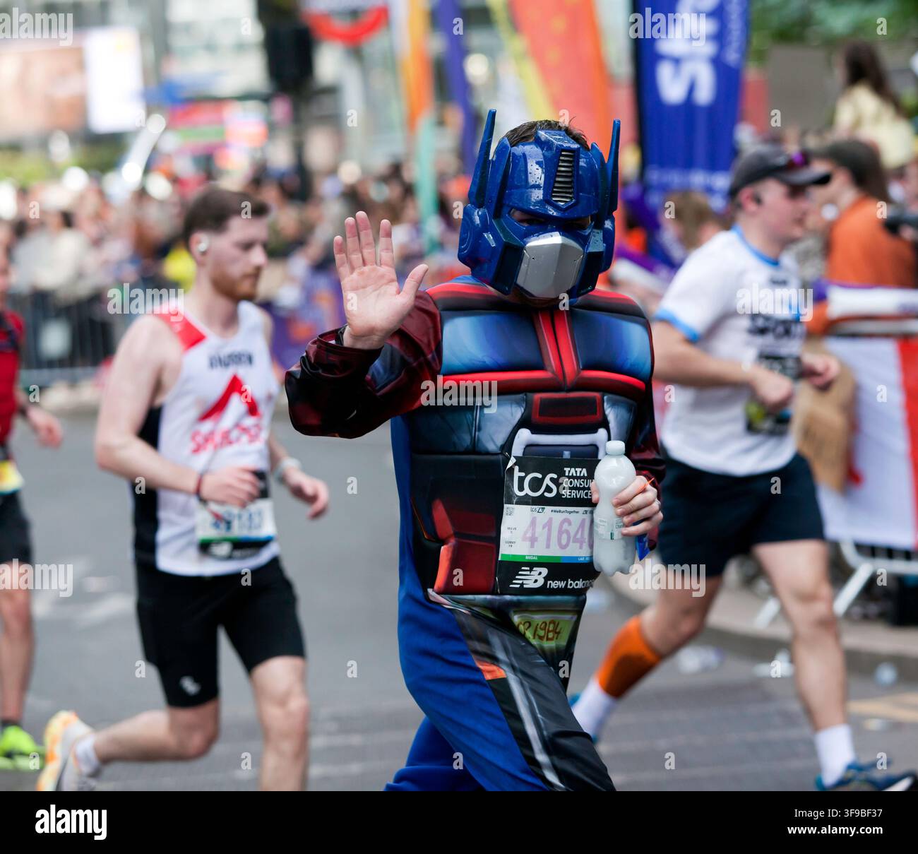 Mike Wilkinson (GBR) winkt und rennt in einem Optimus-Prime-Kostüm während des London-Marathons 2026. Stockfoto