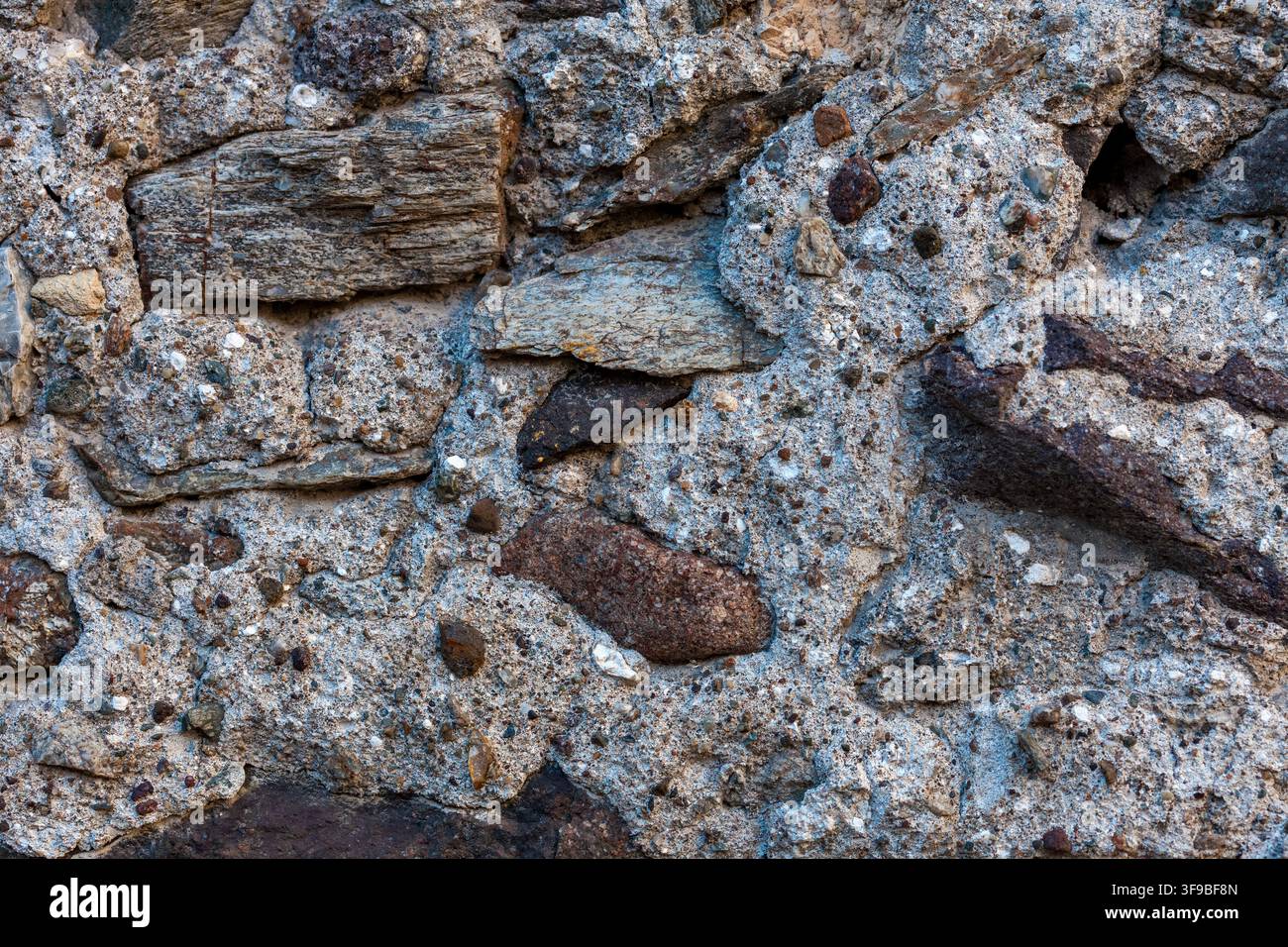 Rustikale Natursteinwandtextur mit groben Gesteinsbrocken und unregelmäßiger verwitterter Oberfläche Stockfoto