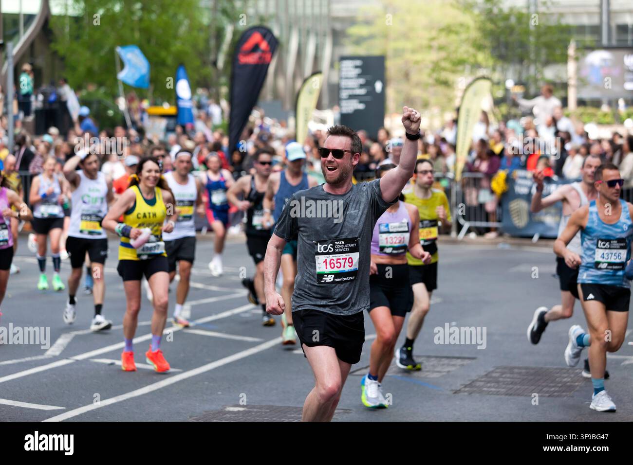 Darren Thomas (GBR) winkt der Menge zu, während er während des London-Marathons 2026 durch Canary Wharf läuft Stockfoto