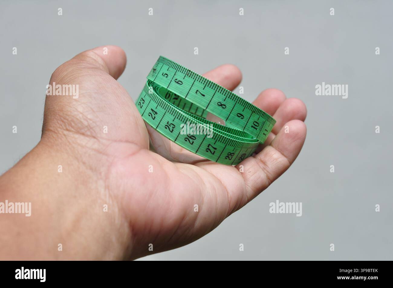 Hand, die ein grünes Maßband hält Stockfoto